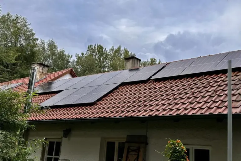 Einfamilienhaus mit rotem Ziegeldach und nachträglich installierter Photovoltaikanlage, ländliche Umgebung