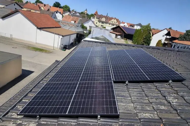 Photovoltaikanlage auf dem Ziegeldach eines Einfamilienhauses in einer deutschen Kleinstadt, mit Blick über Nachbarhäuser und Dächer bei klarem Himmel