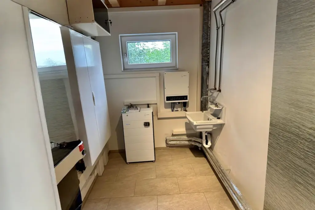 Energiemanagement-System im Hauswirtschaftsraum: FENECON Hybridwechselrichter und Batteriespeicher neben Waschbecken installiert