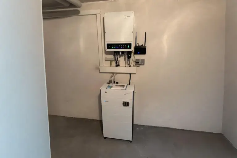 Heimspeicherlösung mit FENECON Batteriespeicher und Hybridwechselrichter in einem sauber installierten Technikraum mit Betonboden