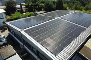 Photovoltaikanlage auf Flachdach eines Firmengebäudes mit umliegender Bebauung und Grünfläche