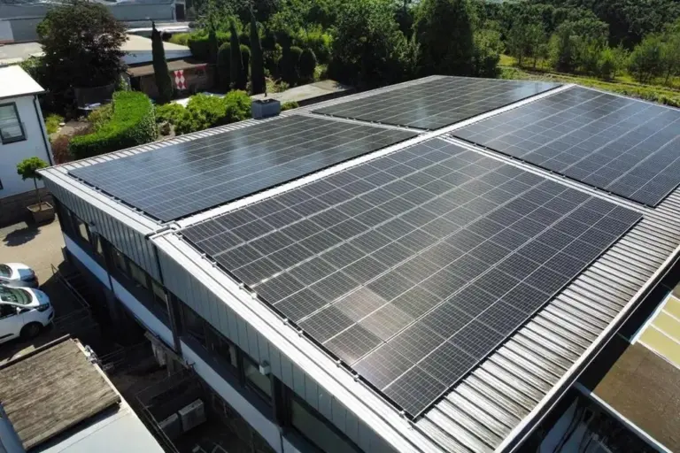 Photovoltaikanlage auf Flachdach eines Firmengebäudes mit umliegender Bebauung und Grünfläche